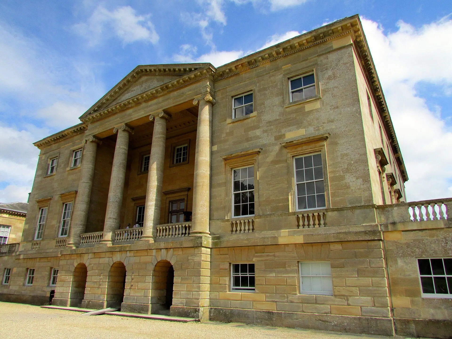 The front facade of Basildon Park in Berkshire under blue sky