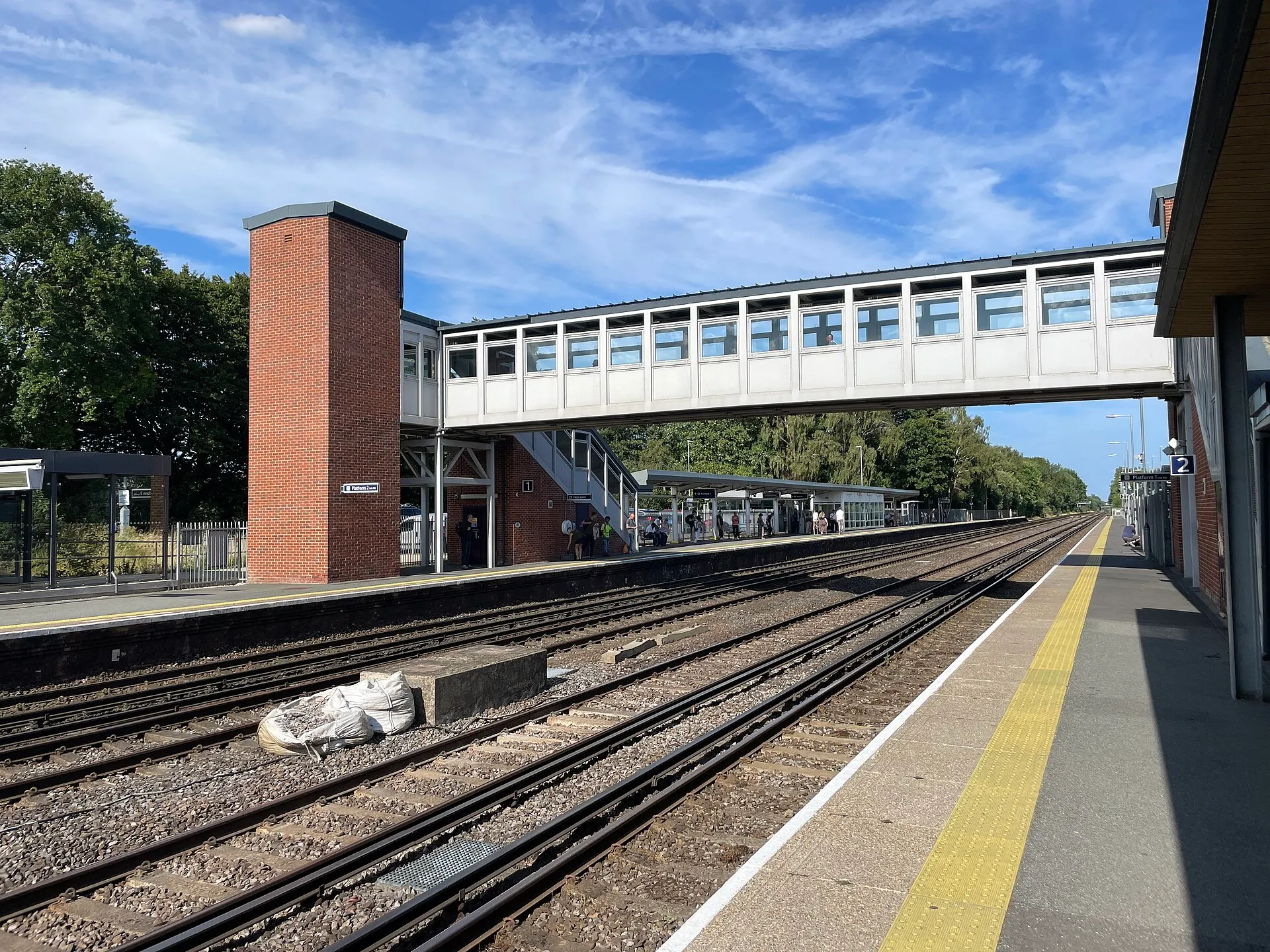 Fleet railway station platforms and footbridge in clear summer weather in 2025