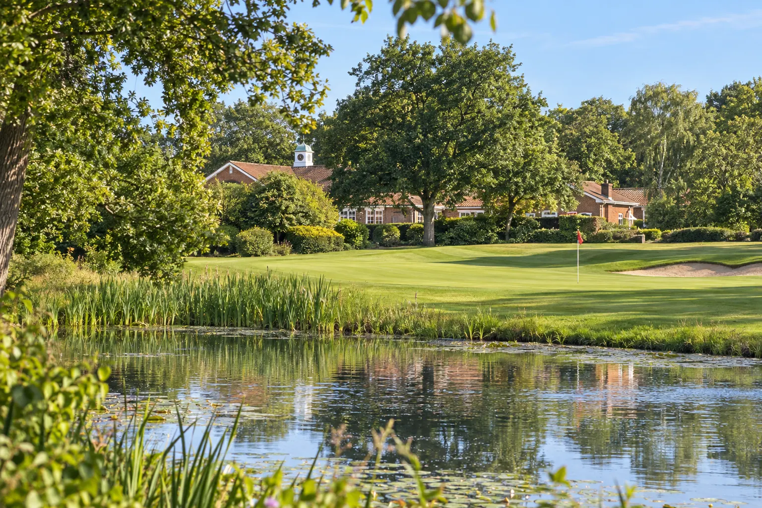 Illustrative green, pond and partially screened clubhouse at Mill Ride, grounded in club photographs