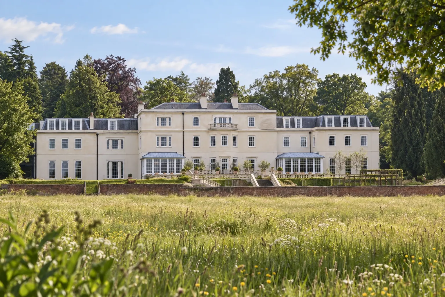 Illustrative spring meadow view of Coworth Park's pale country house