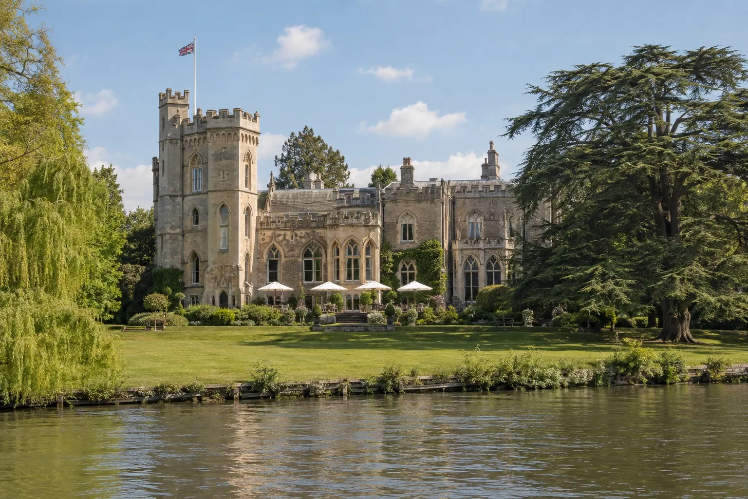 Illustrative sunlit view of Oakley Court's Gothic mansion from the River Thames
